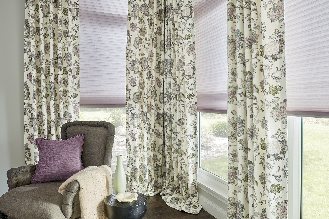 room with fabric drapes, chair with pillows and shades on the windows